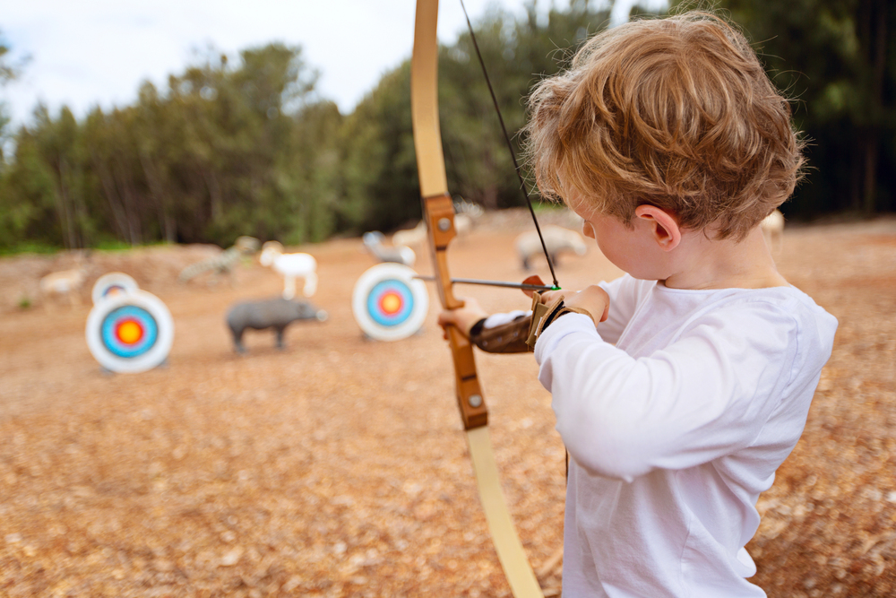 Child with bow and arrow shooting target