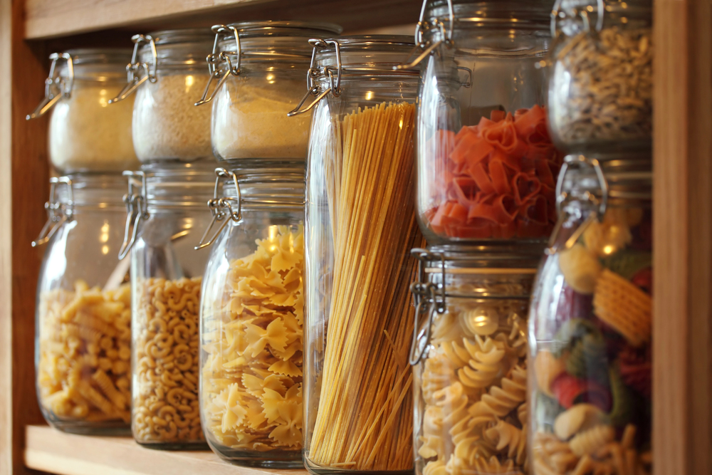 Glass jars full of pasta, sitting on a shelf.